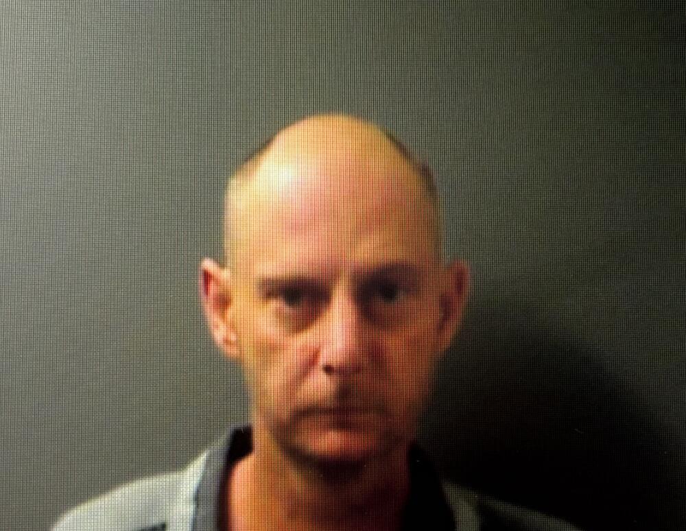 Bald man posing for booking photo