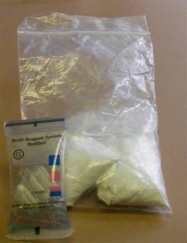 A bag of drugs next to a drug testing kit.
