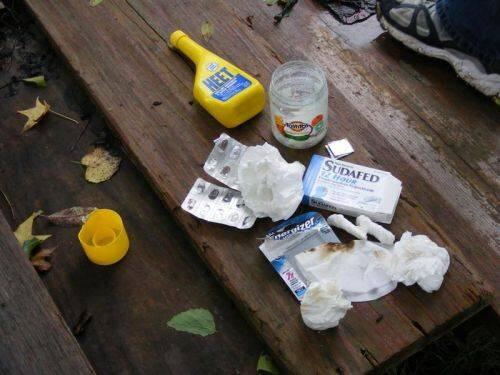 A bottle of antifreeze, a jar, a sudafed medication package, empty battery package, and tissues.