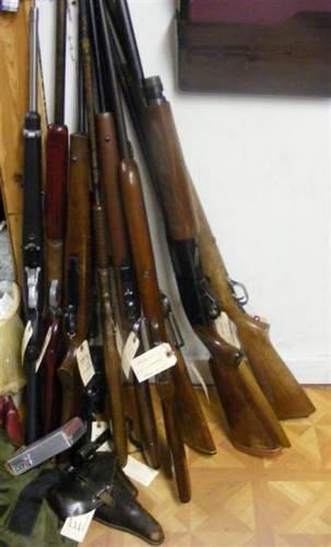 Numerous guns resting against a wall.