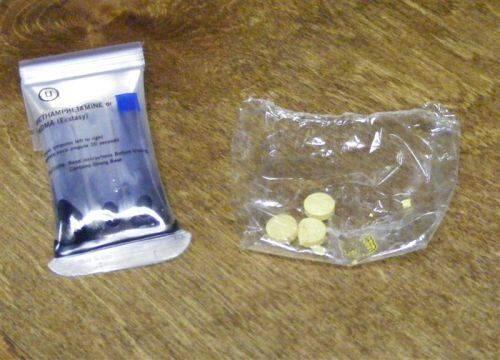 Several pills beside a package stating methamphetamine.