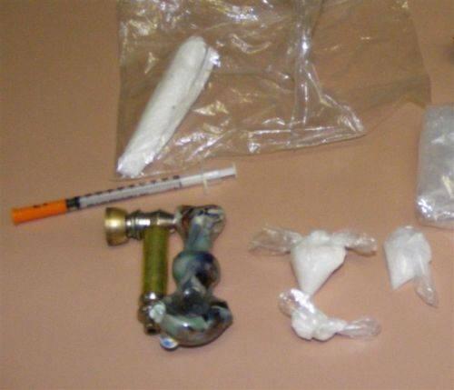 Several bags of drugs with miscellaneous paraphernalia including a syringe.